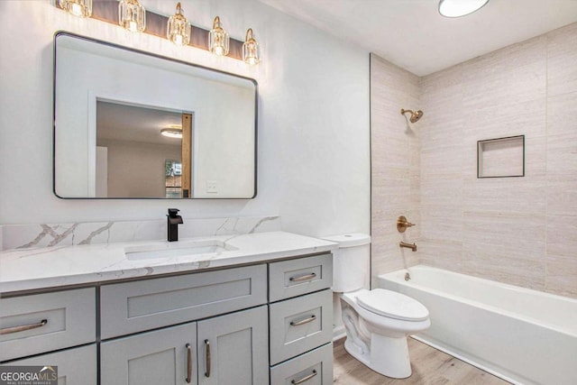 full bathroom featuring vanity, tiled shower / bath, hardwood / wood-style flooring, and toilet