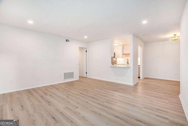 unfurnished living room featuring sink and light wood-type flooring