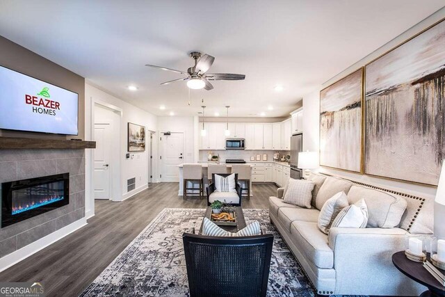 living room featuring a fireplace, wood-type flooring, and ceiling fan