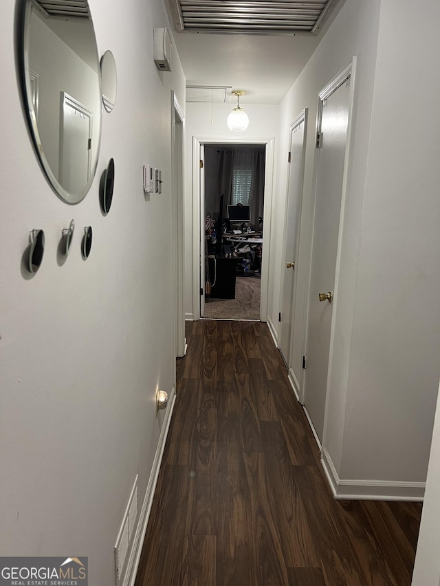 hallway featuring dark wood-style floors, attic access, visible vents, and baseboards