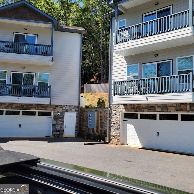 664 Bahn Innsbruck Unit B-4, Helen, GA 30545 - view of side of home featuring an attached garage, stone siding, a balcony, and asphalt driveway