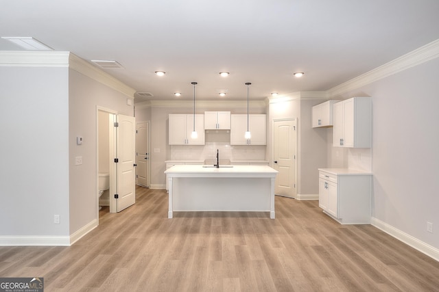 kitchen with a center island with sink, visible vents, a sink, decorative backsplash, and white cabinets