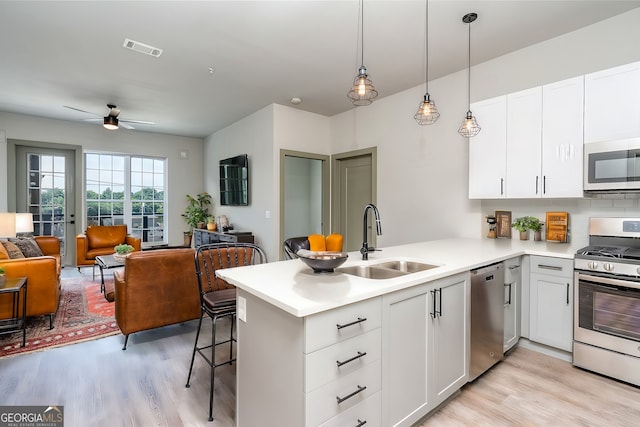 kitchen featuring kitchen peninsula, appliances with stainless steel finishes, ceiling fan, sink, and white cabinets