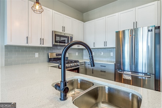 kitchen featuring appliances with stainless steel finishes, tasteful backsplash, light stone counters, pendant lighting, and white cabinets