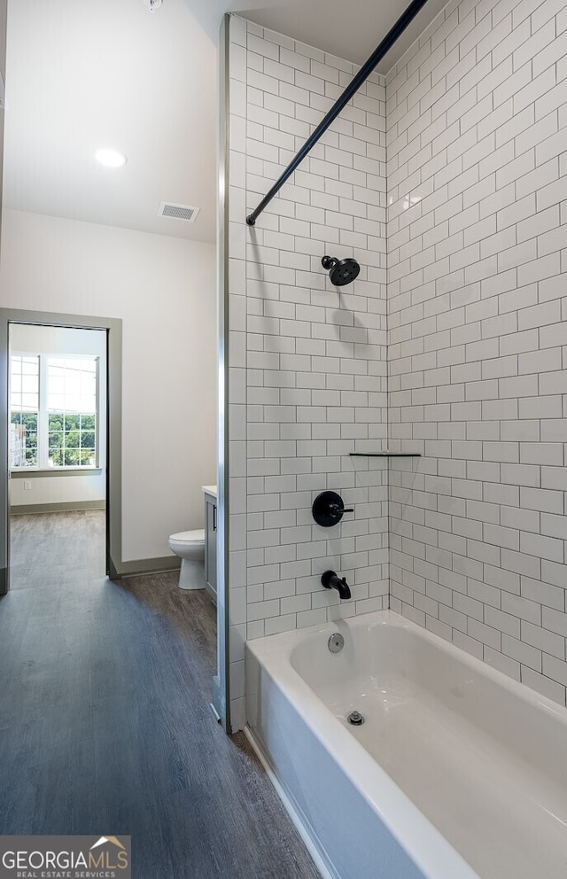 bathroom featuring hardwood / wood-style floors, toilet, and tiled shower / bath