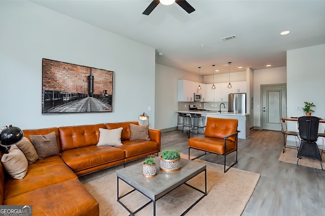 living room featuring ceiling fan and light hardwood / wood-style floors