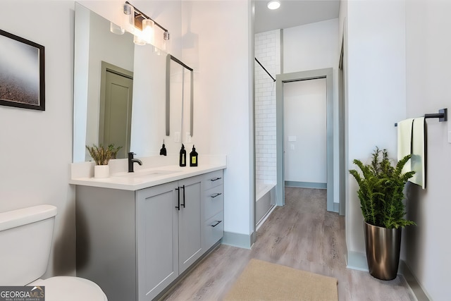 full bathroom with hardwood / wood-style flooring, vanity, toilet, and shower / washtub combination