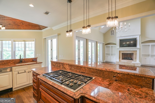 kitchen with hanging light fixtures, stainless steel gas stovetop, an inviting chandelier, dark stone countertops, and dark wood-type flooring