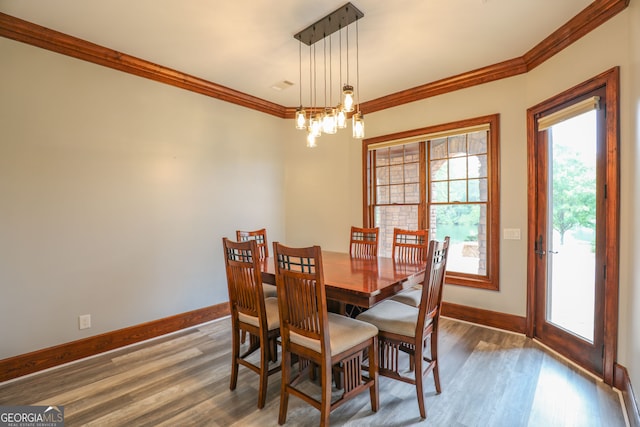 dining space with an inviting chandelier, crown molding, and wood-type flooring