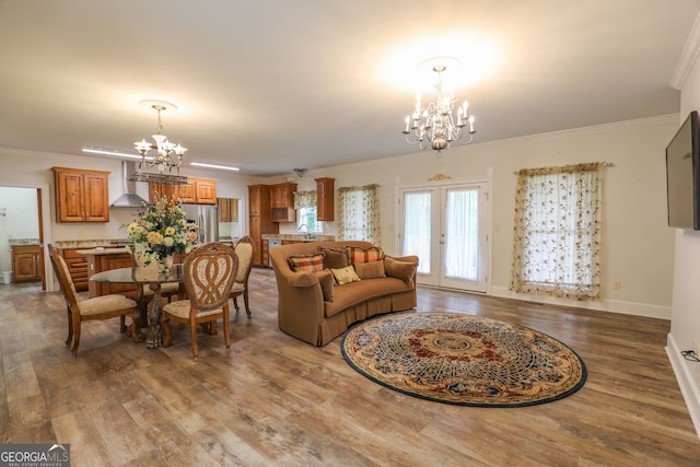 living room featuring an inviting chandelier, crown molding, french doors, and hardwood / wood-style flooring