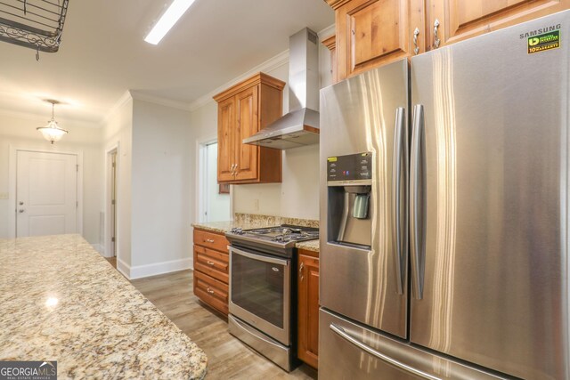 kitchen featuring wall chimney range hood, stainless steel appliances, hanging light fixtures, light stone counters, and light hardwood / wood-style floors