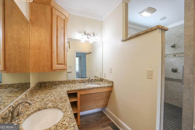 bathroom featuring ornamental molding, a tile shower, hardwood / wood-style floors, and double sink vanity