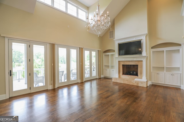 unfurnished living room with a healthy amount of sunlight, wood-type flooring, built in shelves, and a fireplace