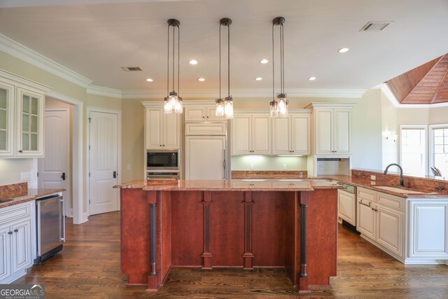 kitchen featuring dark wood-type flooring, light stone countertops, hanging light fixtures, and built in appliances