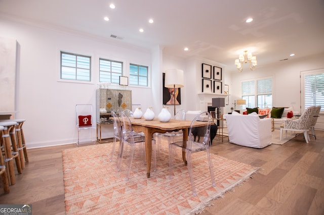 dining space with an inviting chandelier, light wood-type flooring, and ornamental molding