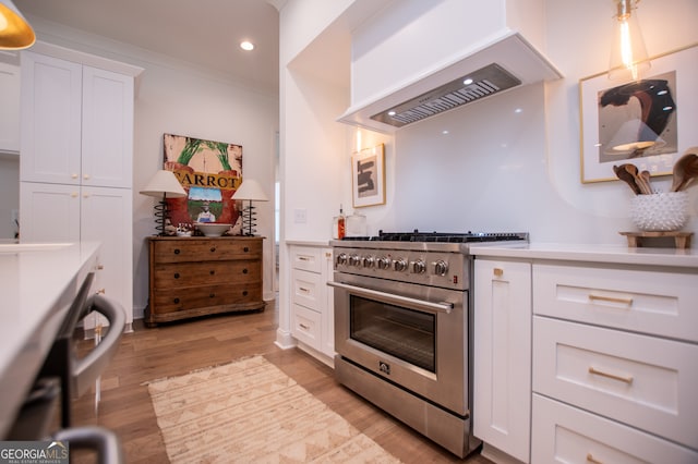 kitchen featuring white cabinetry, custom exhaust hood, light wood-type flooring, ornamental molding, and stainless steel range