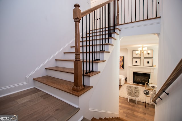 staircase with hardwood / wood-style flooring and an inviting chandelier