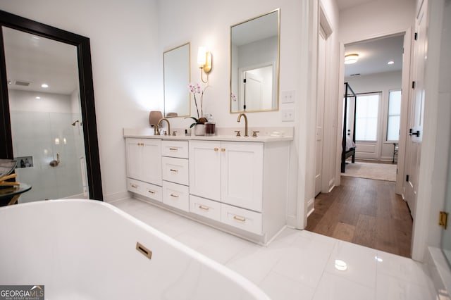 bathroom featuring wood-type flooring, double sink vanity, and independent shower and bath