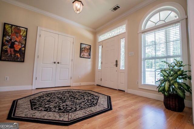 foyer entrance with ornamental molding and light wood-type flooring