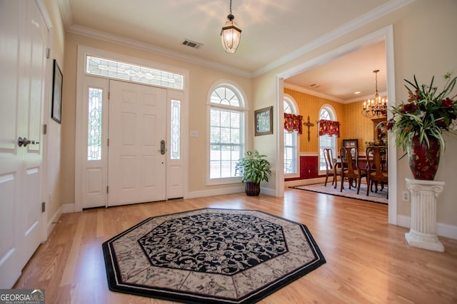 foyer entrance with a notable chandelier, crown molding, and wood-type flooring