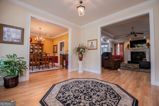 foyer entrance with hardwood / wood-style flooring, ceiling fan with notable chandelier, and ornamental molding