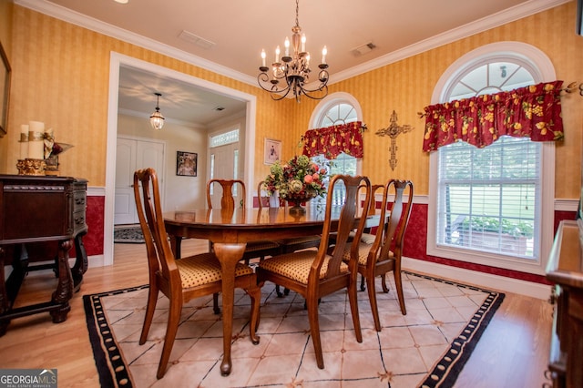 dining space with an inviting chandelier, crown molding, and light hardwood / wood-style floors