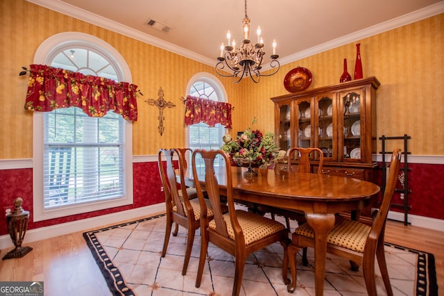 dining space with ornamental molding, an inviting chandelier, and light hardwood / wood-style floors