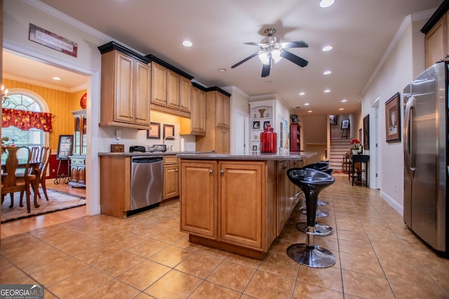 kitchen featuring light tile patterned floors, crown molding, appliances with stainless steel finishes, a kitchen breakfast bar, and ceiling fan with notable chandelier