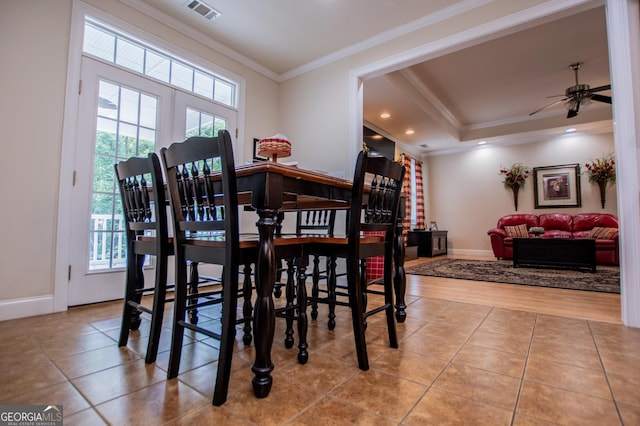 dining room with a raised ceiling, crown molding, light tile patterned flooring, and ceiling fan