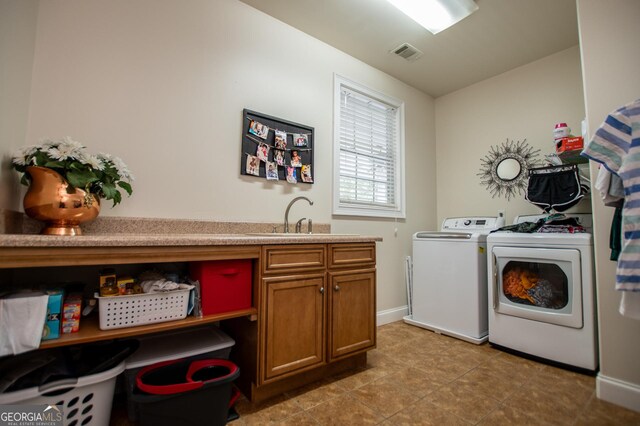 washroom featuring light tile patterned flooring, cabinets, sink, and washer and dryer