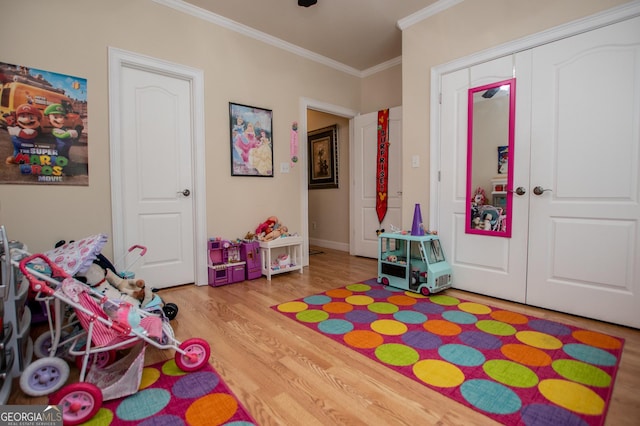 playroom with crown molding and light hardwood / wood-style flooring