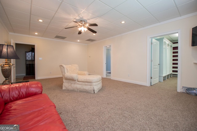 living room with crown molding, carpet, a drop ceiling, and ceiling fan