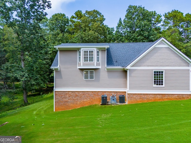 back of house featuring a lawn and central air condition unit