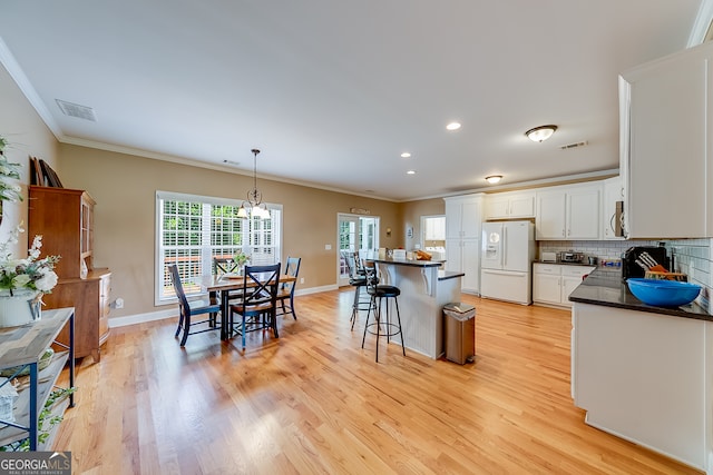 kitchen with tasteful backsplash, white fridge with ice dispenser, light hardwood / wood-style flooring, and a kitchen bar