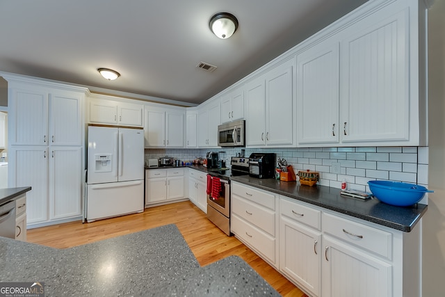 kitchen featuring decorative backsplash, appliances with stainless steel finishes, light hardwood / wood-style floors, and white cabinetry