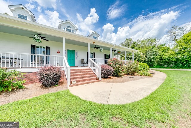 view of front of house with ceiling fan, a front yard, and covered porch