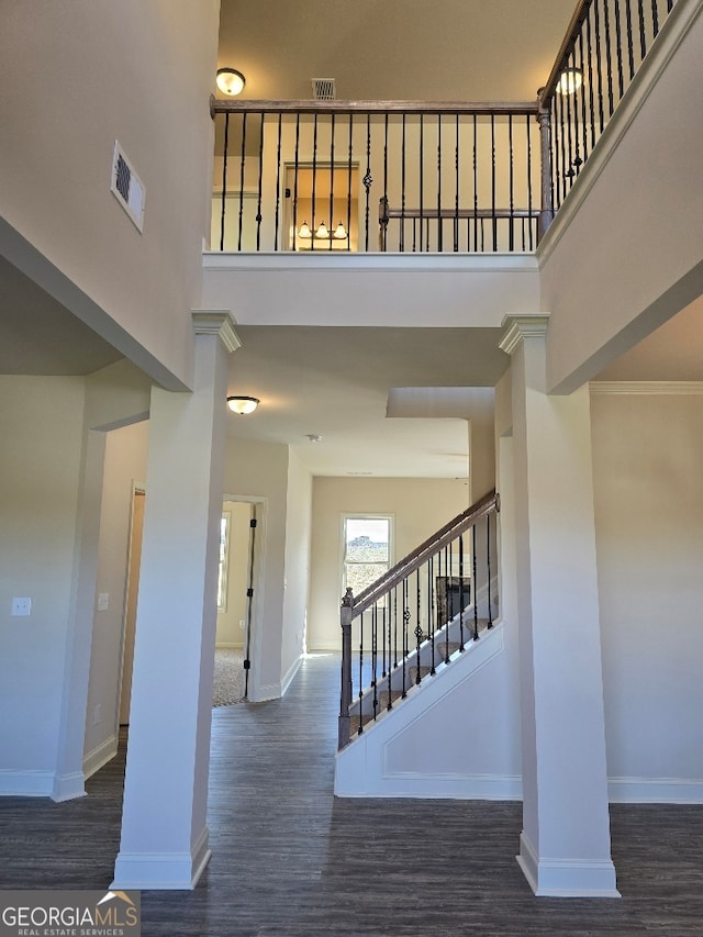 staircase with a towering ceiling, baseboards, and wood finished floors