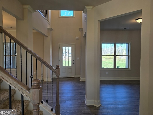 foyer featuring stairway, visible vents, baseboards, and wood finished floors