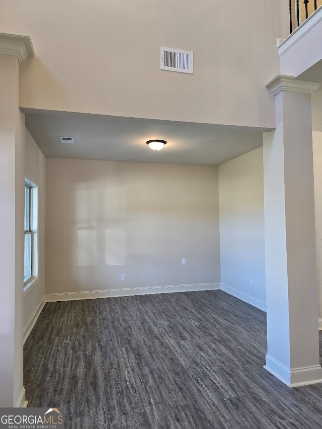 spare room with dark wood-style floors, ornate columns, visible vents, and baseboards