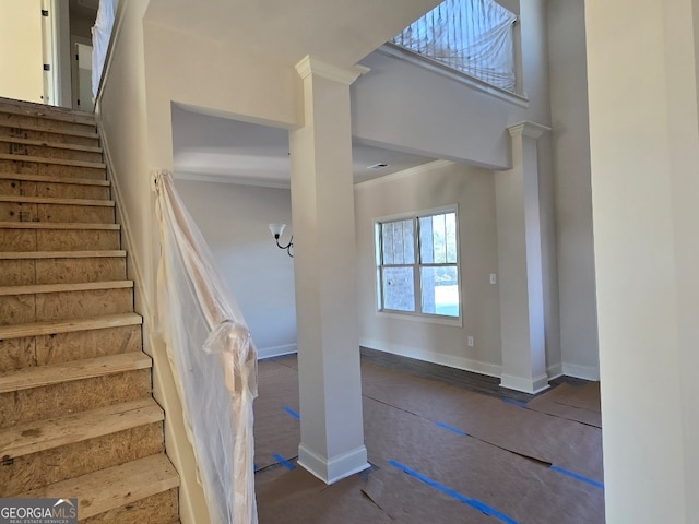 staircase featuring ornamental molding, decorative columns, and a high ceiling