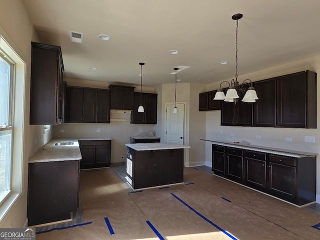 kitchen featuring hanging light fixtures, dark brown cabinetry, a notable chandelier, ventilation hood, and a kitchen island