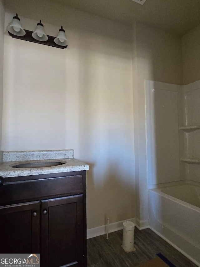 bathroom featuring sink, hardwood / wood-style flooring, and washtub / shower combination