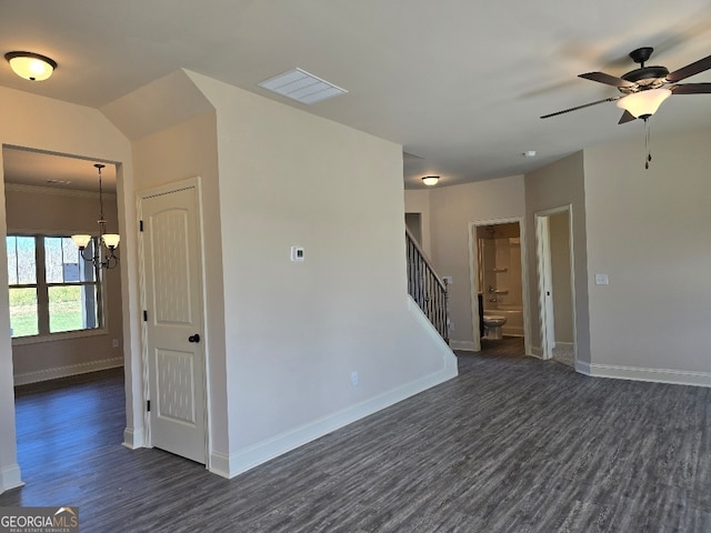 spare room with ceiling fan with notable chandelier, dark wood-type flooring, visible vents, baseboards, and stairs