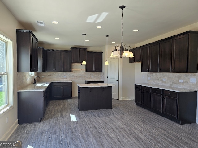 kitchen with decorative light fixtures, a sink, baseboards, and wood finished floors