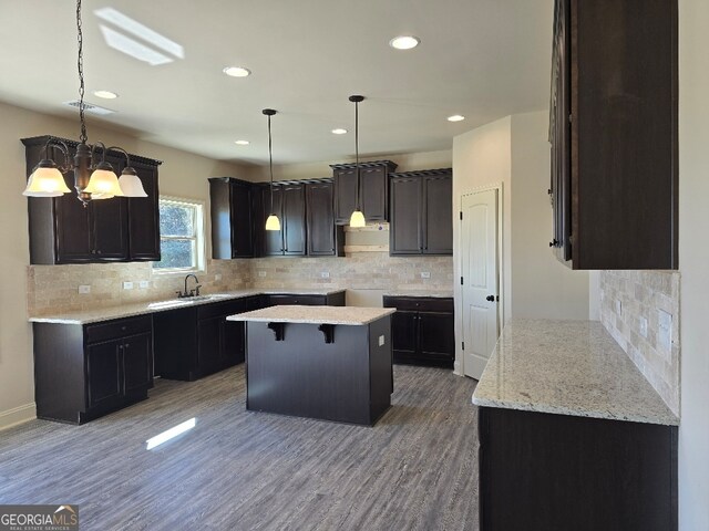 kitchen featuring decorative light fixtures, a sink, a notable chandelier, and wood finished floors