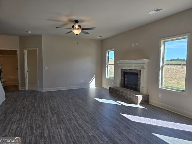 unfurnished living room featuring dark wood-style flooring, a brick fireplace, visible vents, and baseboards