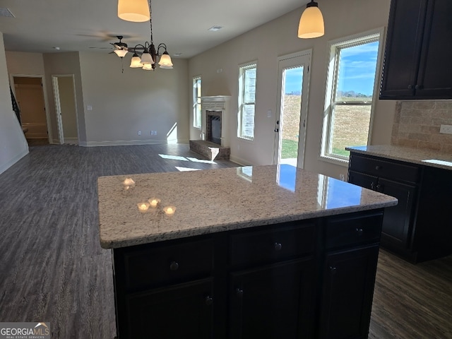 kitchen featuring dark wood finished floors, a fireplace, tasteful backsplash, open floor plan, and a kitchen island