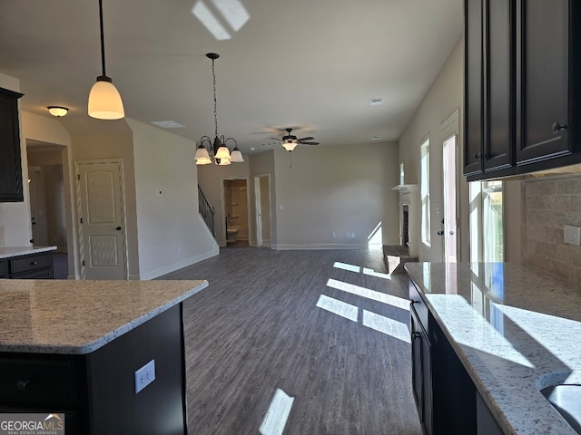 kitchen featuring tasteful backsplash, baseboards, dark wood finished floors, decorative light fixtures, and a fireplace