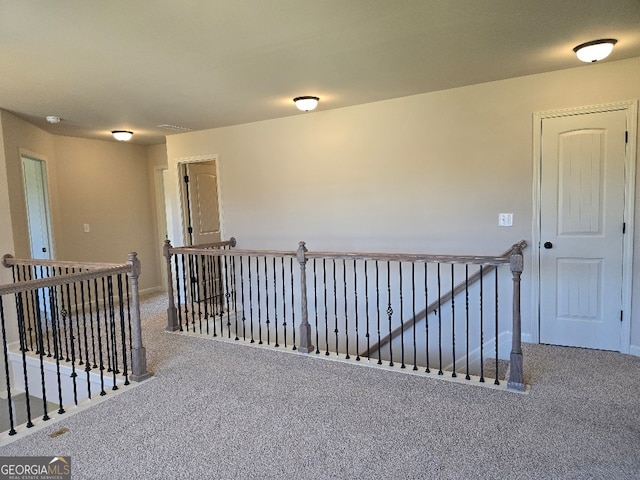 hallway with carpet floors, baseboards, and an upstairs landing