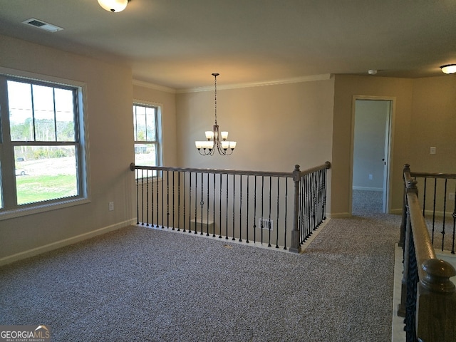 empty room with baseboards, visible vents, ornamental molding, an inviting chandelier, and carpet floors